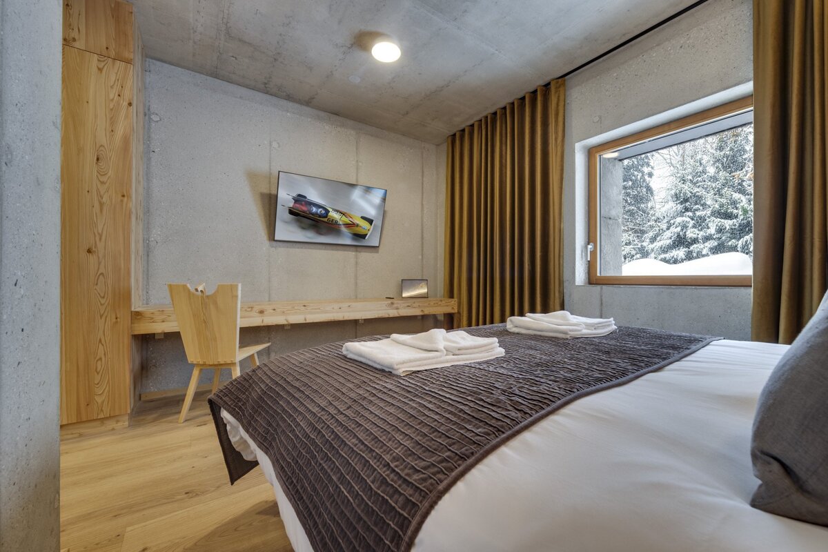 A bedroom with a bed a desk and a flat screen tv