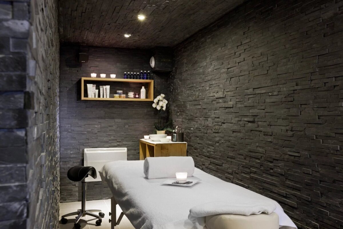 A massage table in a room with black brick walls