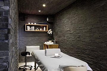 A massage table in a room with black brick walls