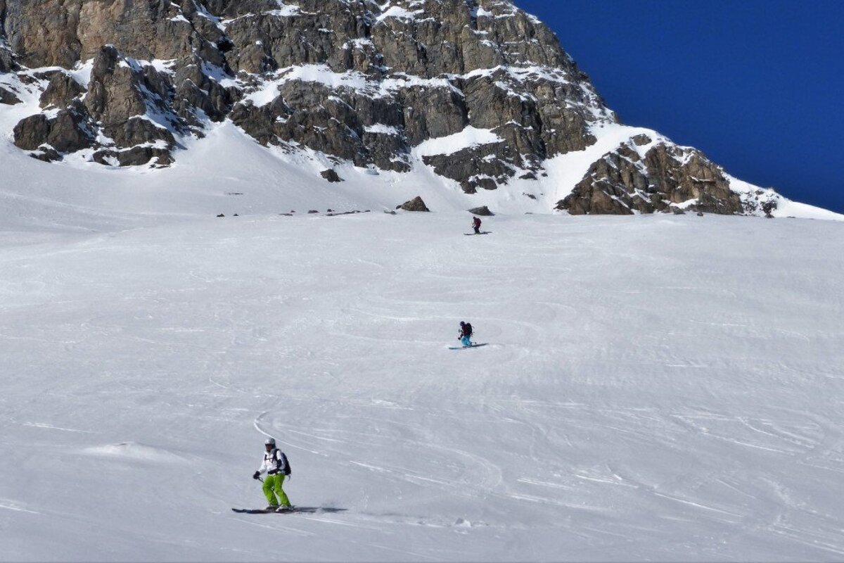 Skiers on a snowy slope with a mountain in the background