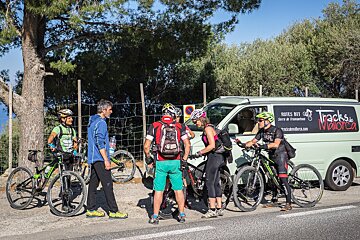 A group of cyclists are standing in front of a van that says tracks de mallorca
