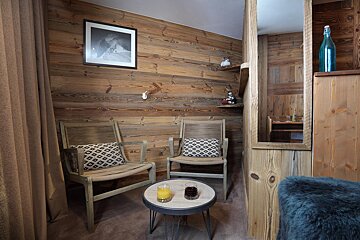 A wooden room with two chairs and a small table