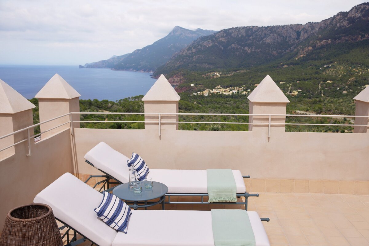 Two lounge chairs sit on a balcony overlooking the ocean