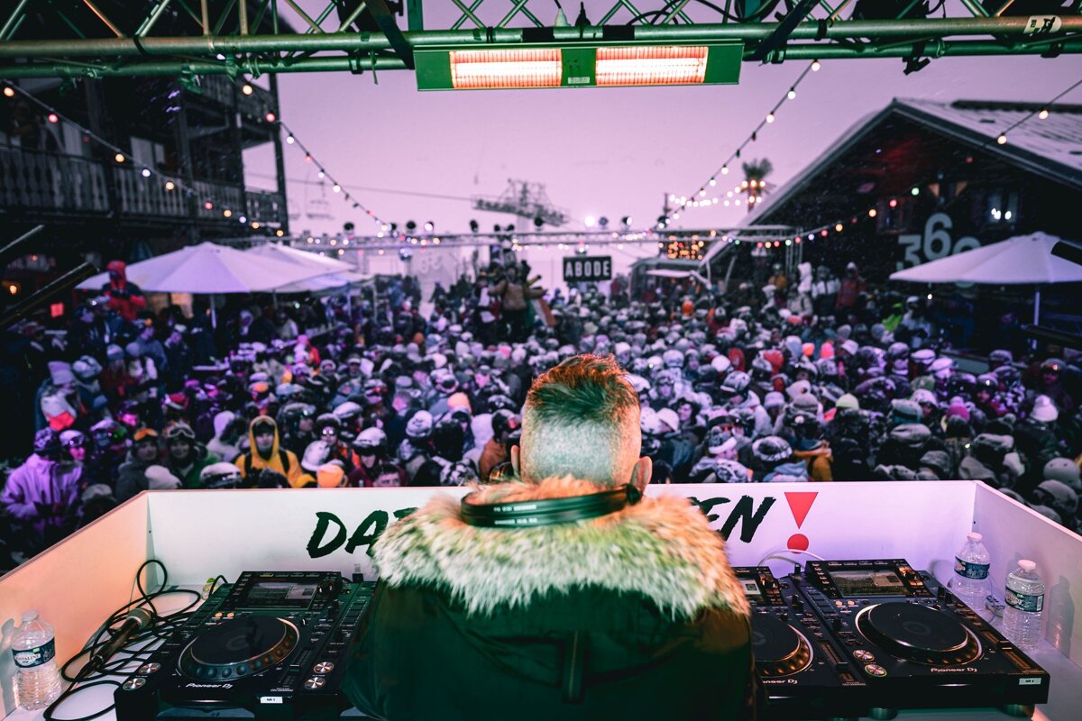 A dj playing music in front of a crowd with a sign that says da en