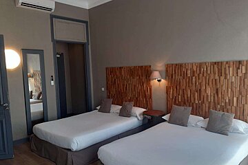 A hotel room with two beds and a wooden headboard