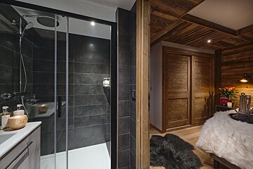 A bathroom with black tiles and a walk in shower