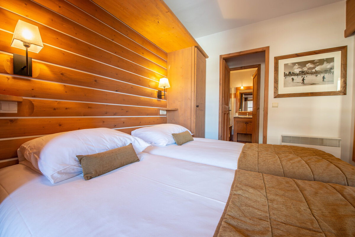 A bedroom with two beds and a picture on the wall