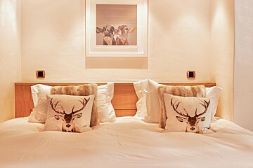 A bed with two pillows with deer faces on them