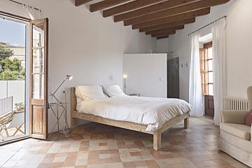 A bedroom with a large bed and a chair