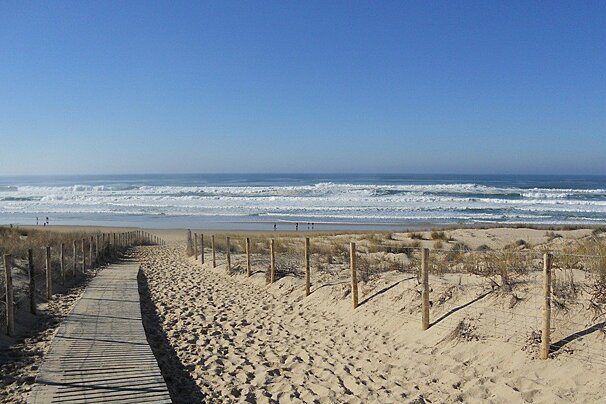 a wooden walkway to a beach adn ocean