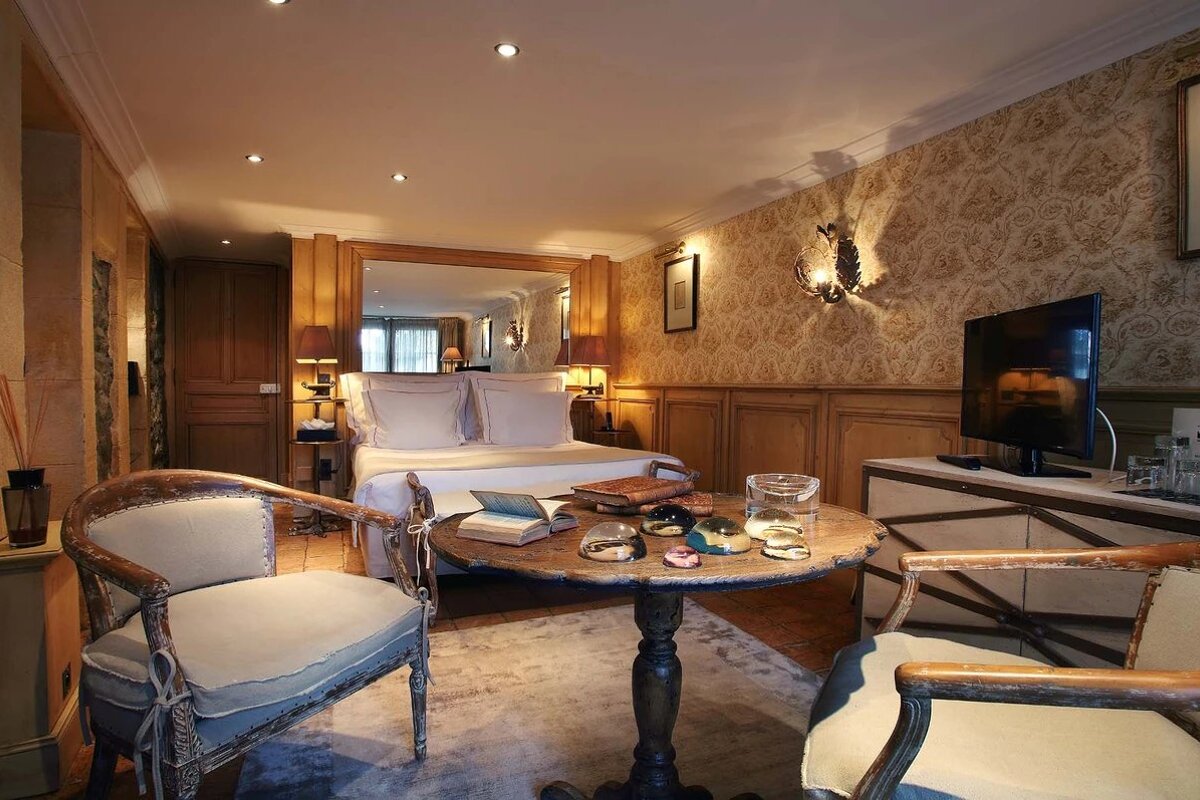 A bedroom with a table and chairs in front of a bed