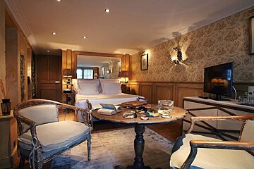 A bedroom with a table and chairs in front of a bed