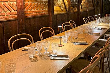 A long wooden table with glasses and utensils on it