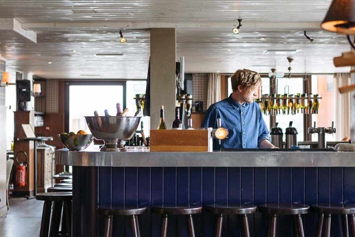 A man stands behind a bar in a restaurant