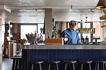 A man stands behind a bar in a restaurant