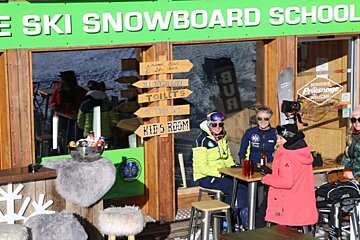 A group of people sitting outside of ole ski snowboard school