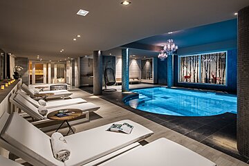 A large indoor swimming pool with a chandelier hanging from the ceiling