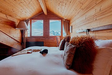 A bedroom with a bed and a window with mountains in the background