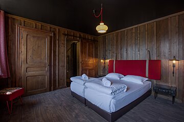 A bedroom with wood paneling and a red headboard