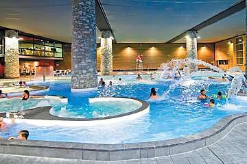 A group of people are swimming in a large indoor pool