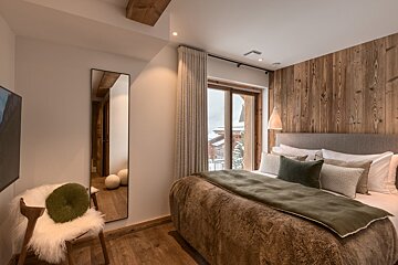 A bedroom with a large bed and a mirror