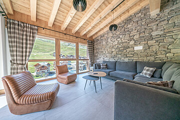 A living room with a stone wall and wooden beams