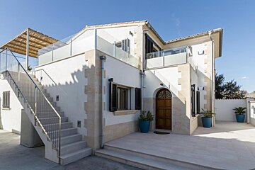 A white house with stairs leading up to the second floor