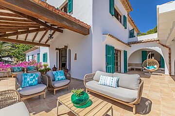 A patio with a couch and chairs with blue pillows