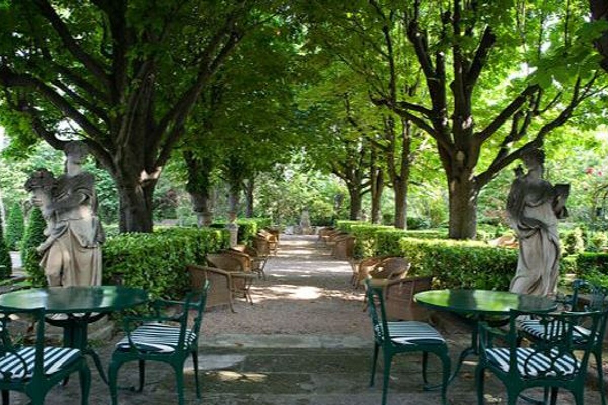 Tree lined path leading off terrace with two stone female statues