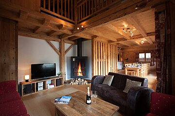 A bottle of champagne sits on a wooden table in a living room