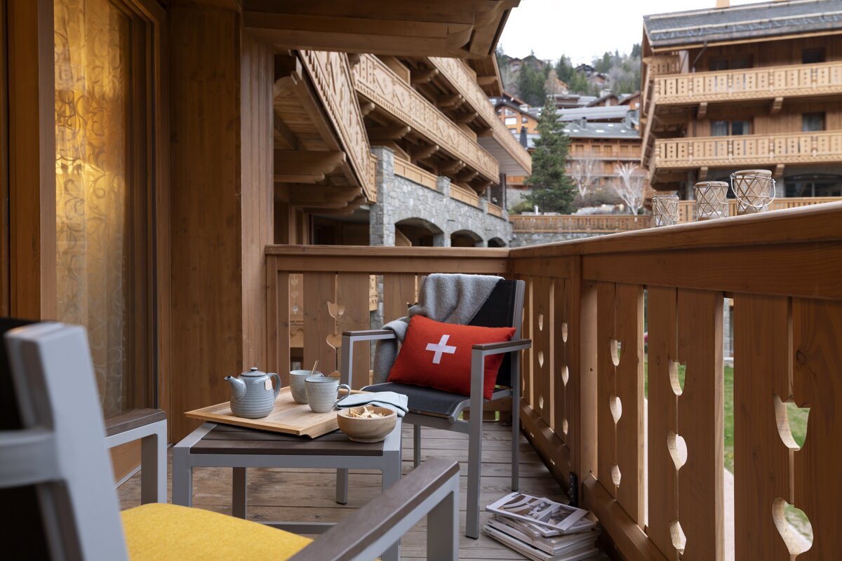 A balcony with a red pillow with a swiss cross on it