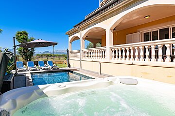 A hot tub sits in front of a large swimming pool