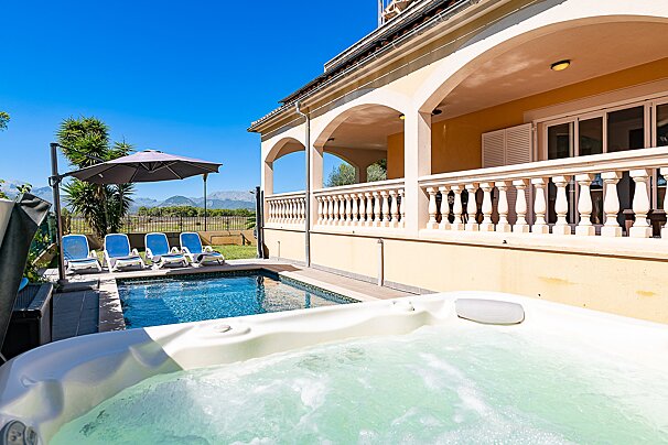 A hot tub sits in front of a large swimming pool