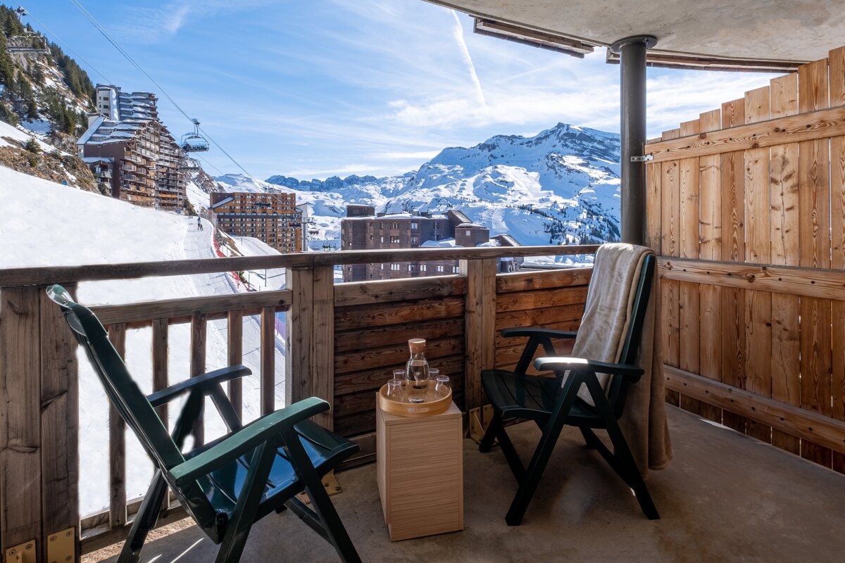 A balcony with two chairs and a bottle of wine