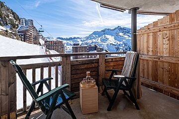 A balcony with two chairs and a bottle of wine