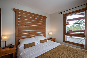 A bedroom with a wooden headboard and a window
