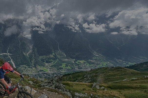 A person riding a bike down a hill with mountains in the background