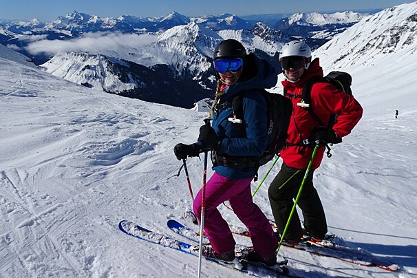 A man and a woman are skiing down a snowy mountain