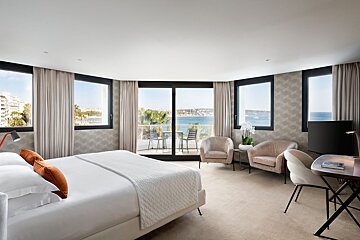 A hotel room with a king size bed and chairs