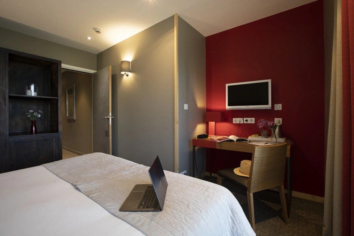 A hotel room with a laptop on the bed