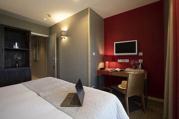 A hotel room with a laptop on the bed