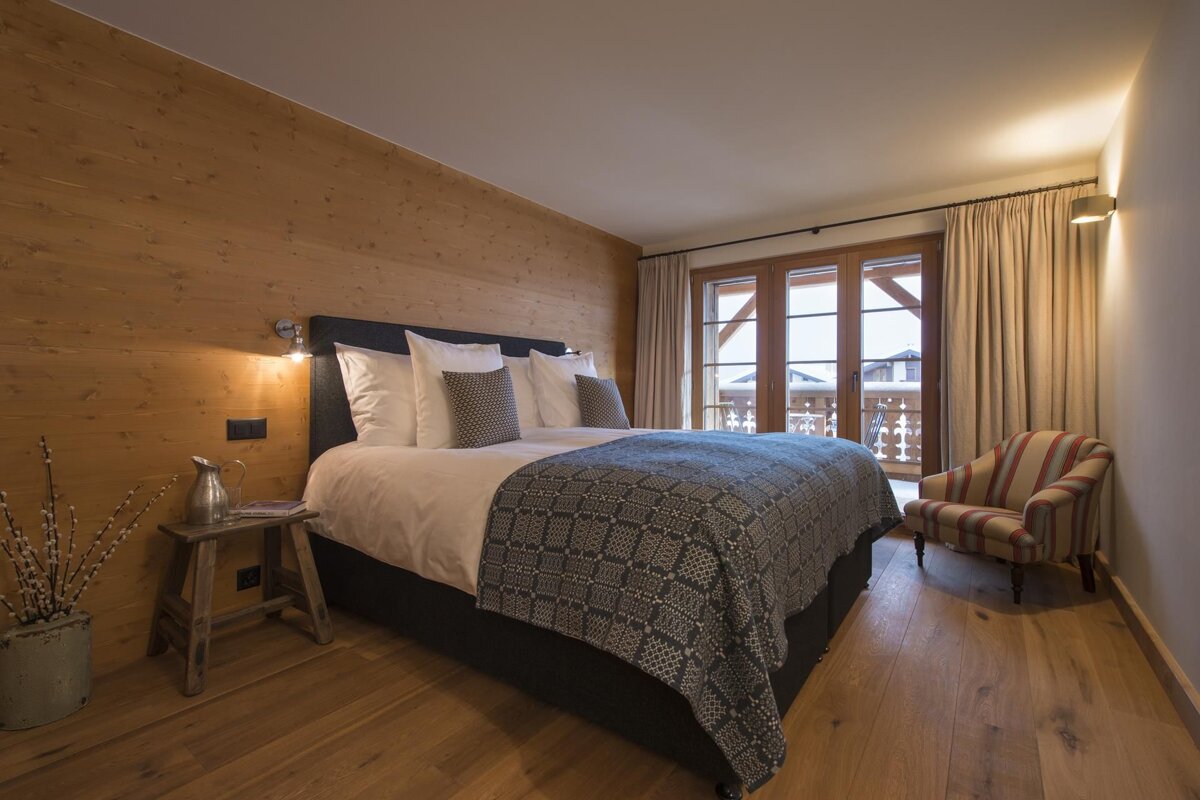 A bedroom with a large bed and a chair