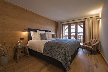 A bedroom with a large bed and a chair