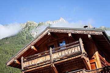 A wooden house with a balcony and mountains in the background