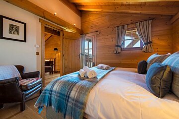 A bedroom with a large bed and a chair