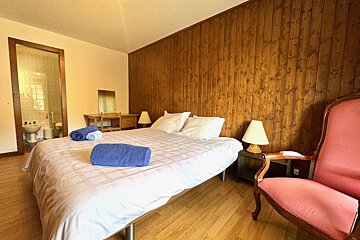 A bedroom with a bed a chair and a lamp