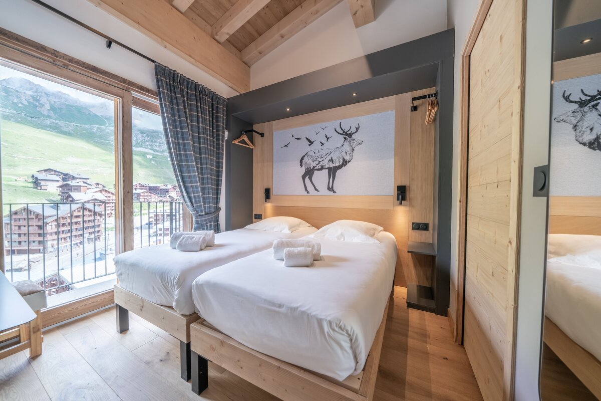 A bedroom with two beds and a picture of a deer on the wall