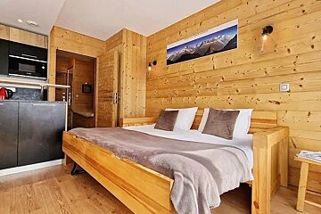A bedroom with a bed and a picture of mountains on the wall