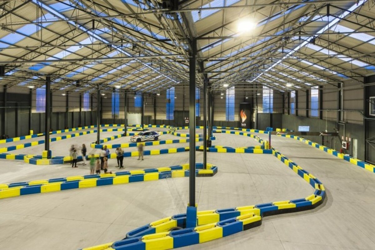 people walking around an indoor karting track