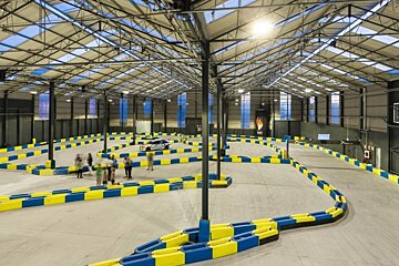 people walking around an indoor karting track